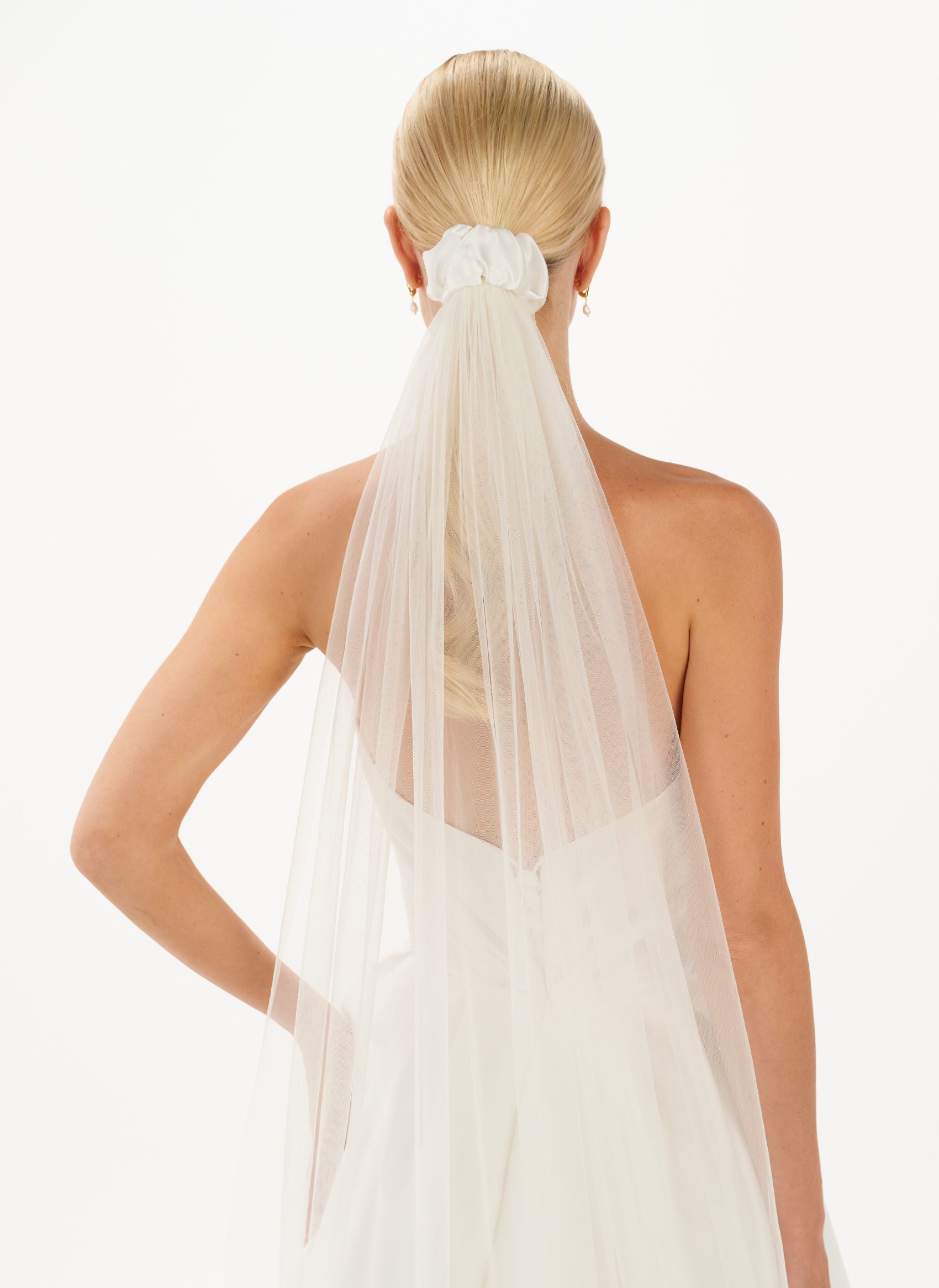 Eine Braut trägt ein gerafftes Seiden-Haarband mit Schleier