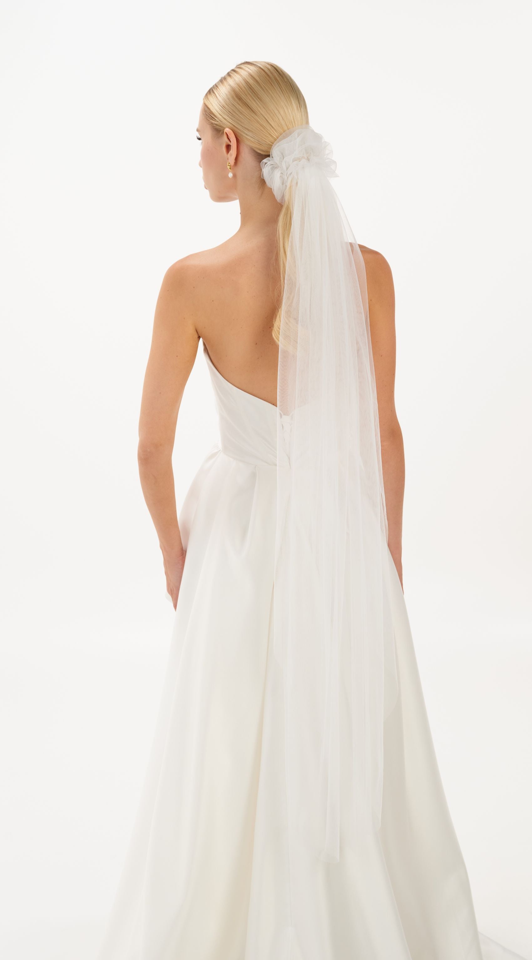 Eine Braut mit gerafften Tüll-Haarband und langem Schleier, hinteransicht