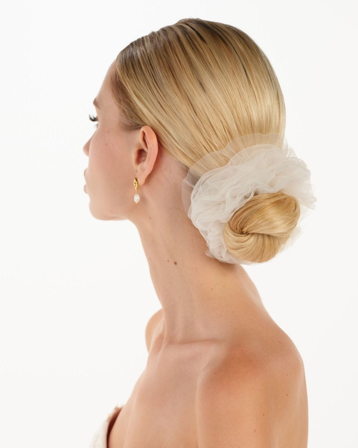 Eine Braut mit einem gerafften Tüll-Haarband im Bun, seitenansicht