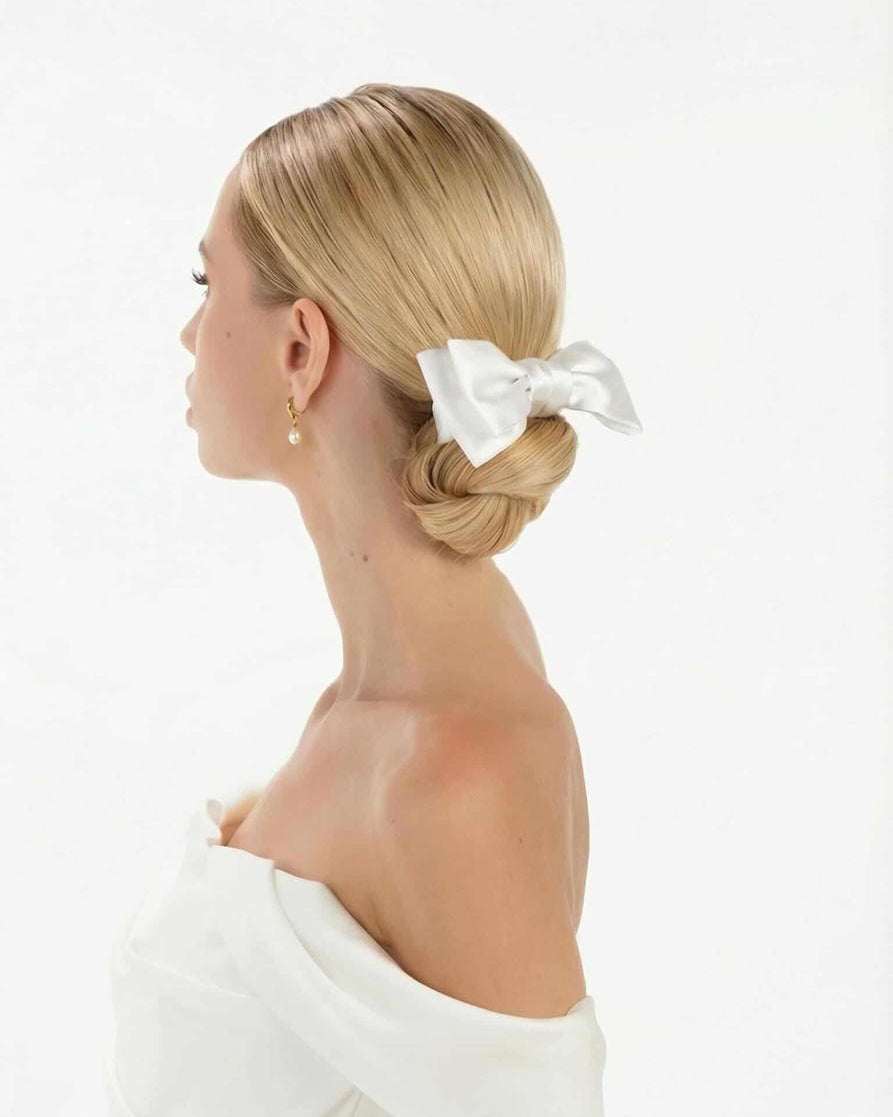 Eine Braut mit cleanen Bun trägt eine kleine Seidenschleife