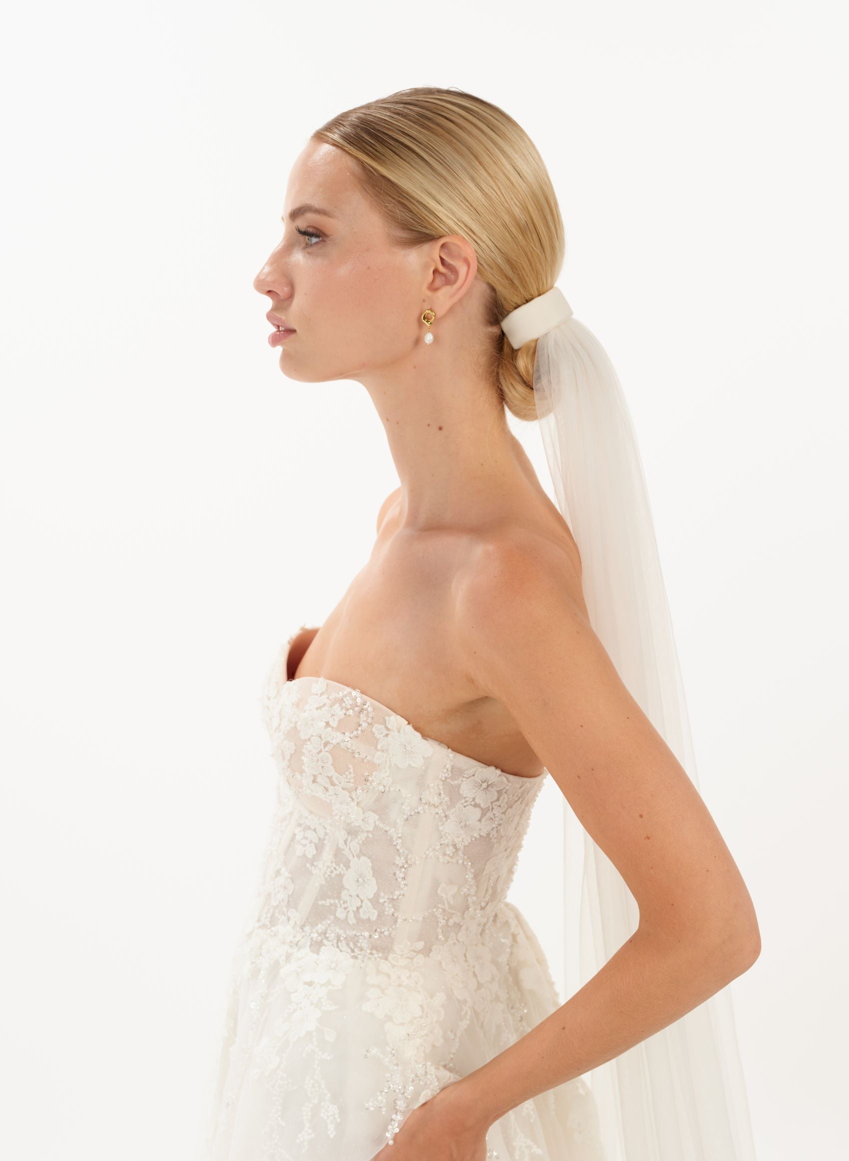 Eine Braut trägt ein Tüll-Haarband & Schleier im Bun, seitenansicht