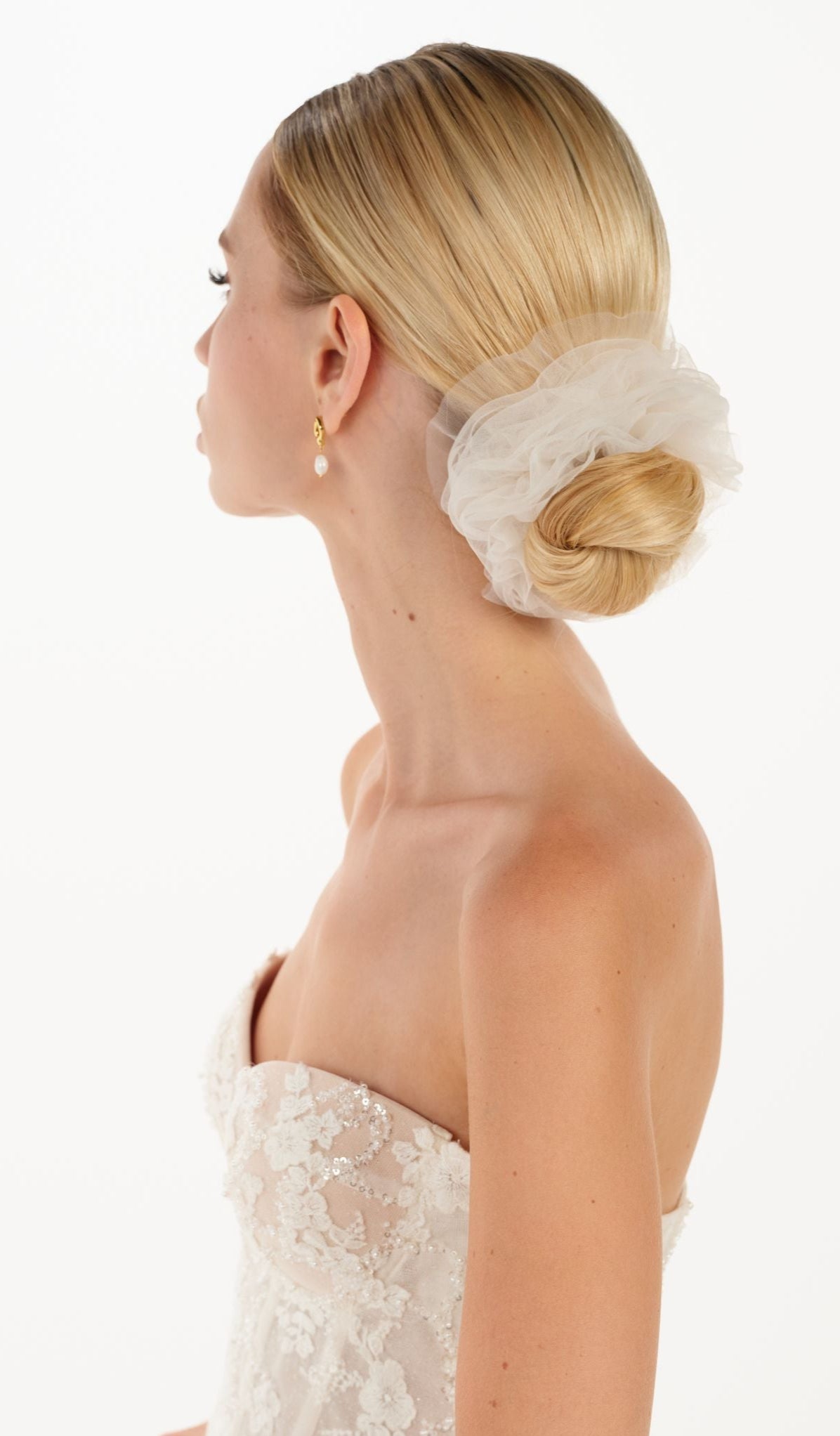 Eine Braut mit einem gerafften Tüll-Haarband im Bun, seitenansicht