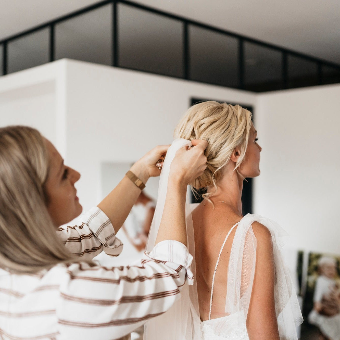 Brautstylist befestigt einen Schleier in der Brautfrisur