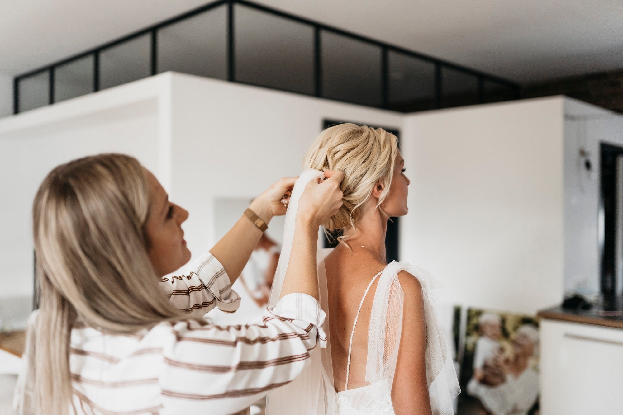 Brautstylist befestigt einen Schleier in der Brautfrisur