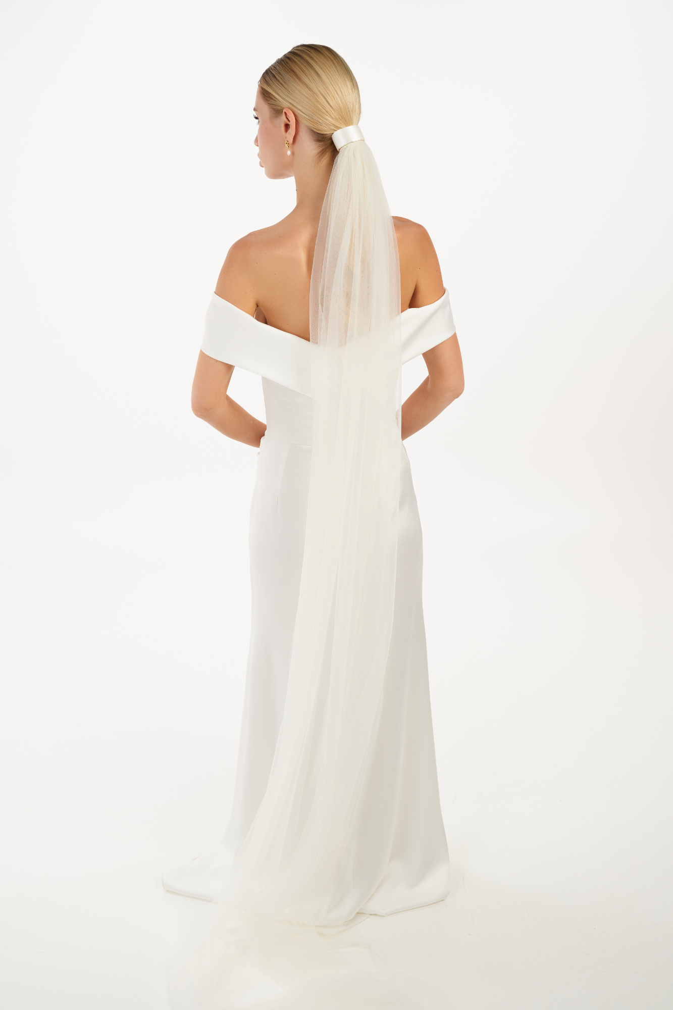 Eine Braut trägt ein Seiden-Haarband & einen langen Schleier an einem Bun