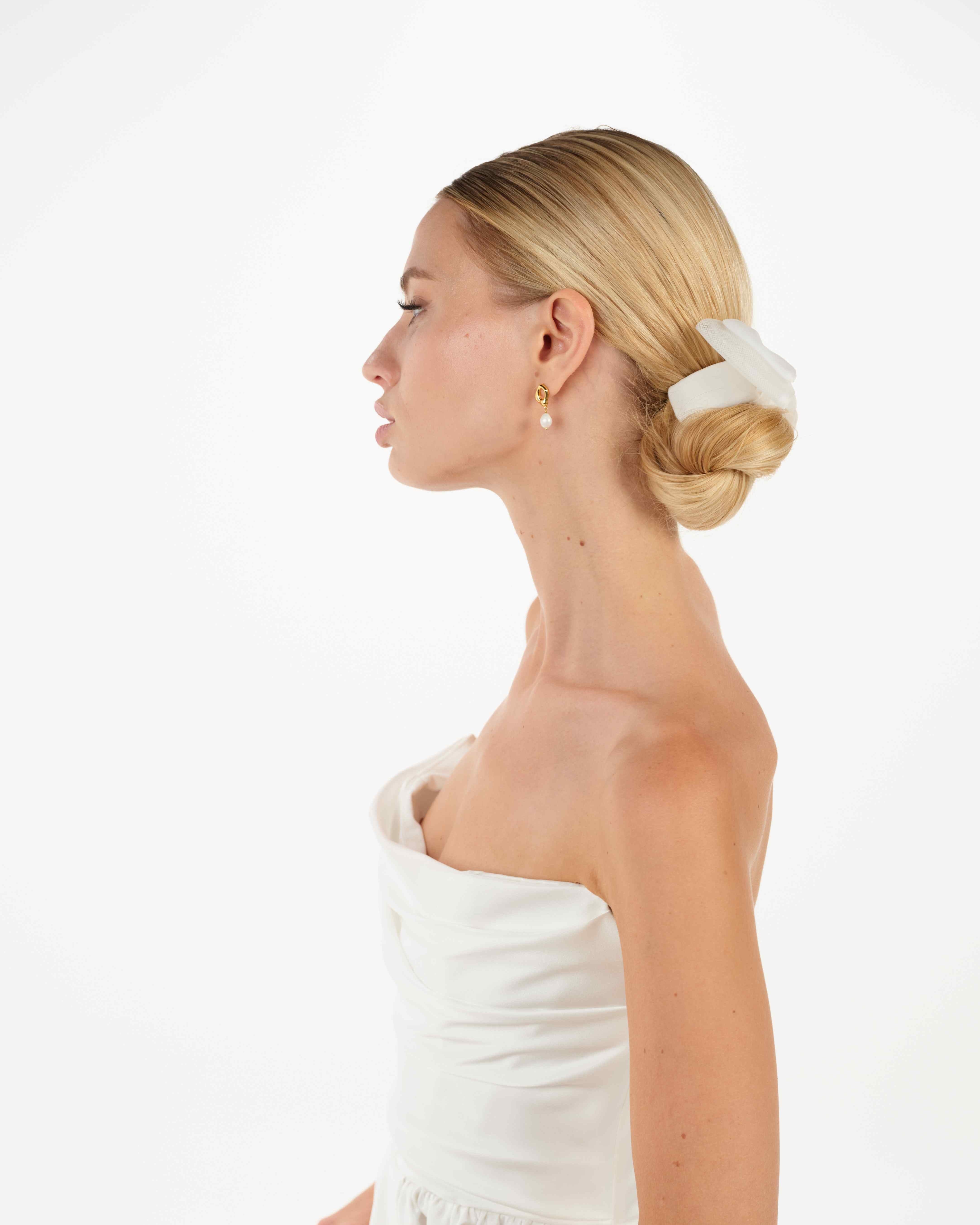 EIne Braut mit Bun und cleanen Kleid trägt eine Tüllschleife und ein Tüllhaarband