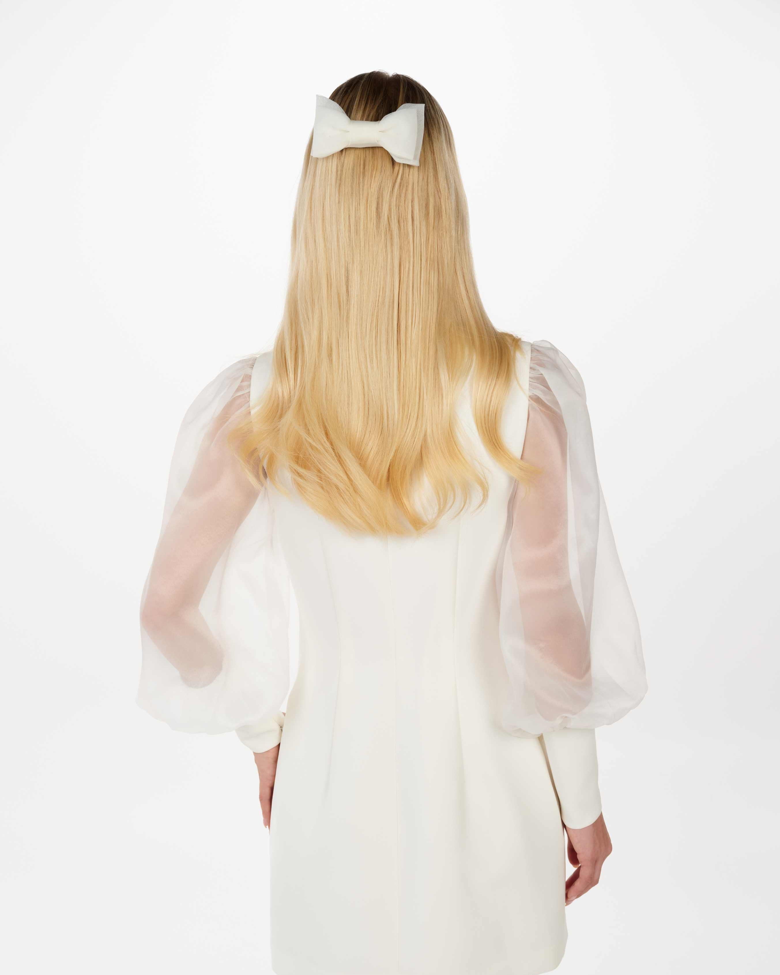 EIne Braut mit offenen Haaren und cleanen Kleid trägt eine Tüllschleife