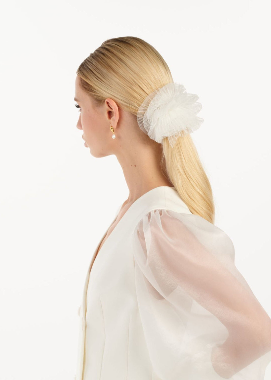 Eine Braut mit einem gerafften Tüll-Haarband im Bun, seitlich