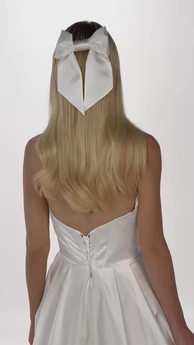 Eine Braut dreht mit Seidenschleife im offenen Haar dreht sich von hinten nach vorne