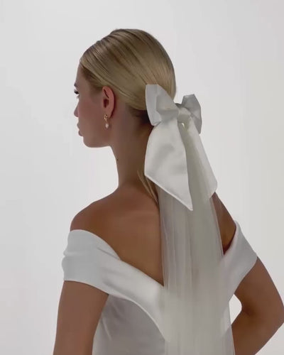 Eine Braut mit Ponytail, Seiden-Haarschleife und Schleier dreht von  hinten nach vorne