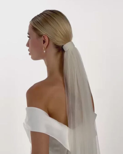 Eine Braut mit Ponytail, Tüll-Haarband und Schleier von  hinten nach vorne