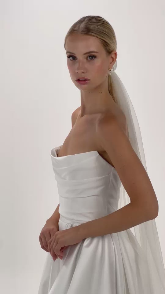 Eine Braut mit gerafften Seiden-Haarband und Schleier dreht sich von vorne nach hinten