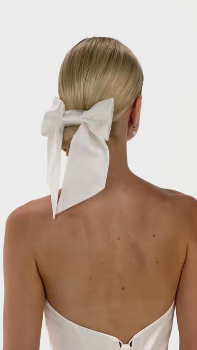 Eine Braut mit Seiden-Haarband und Seidenschleife im Bun dreht sich von hinten nach vorne