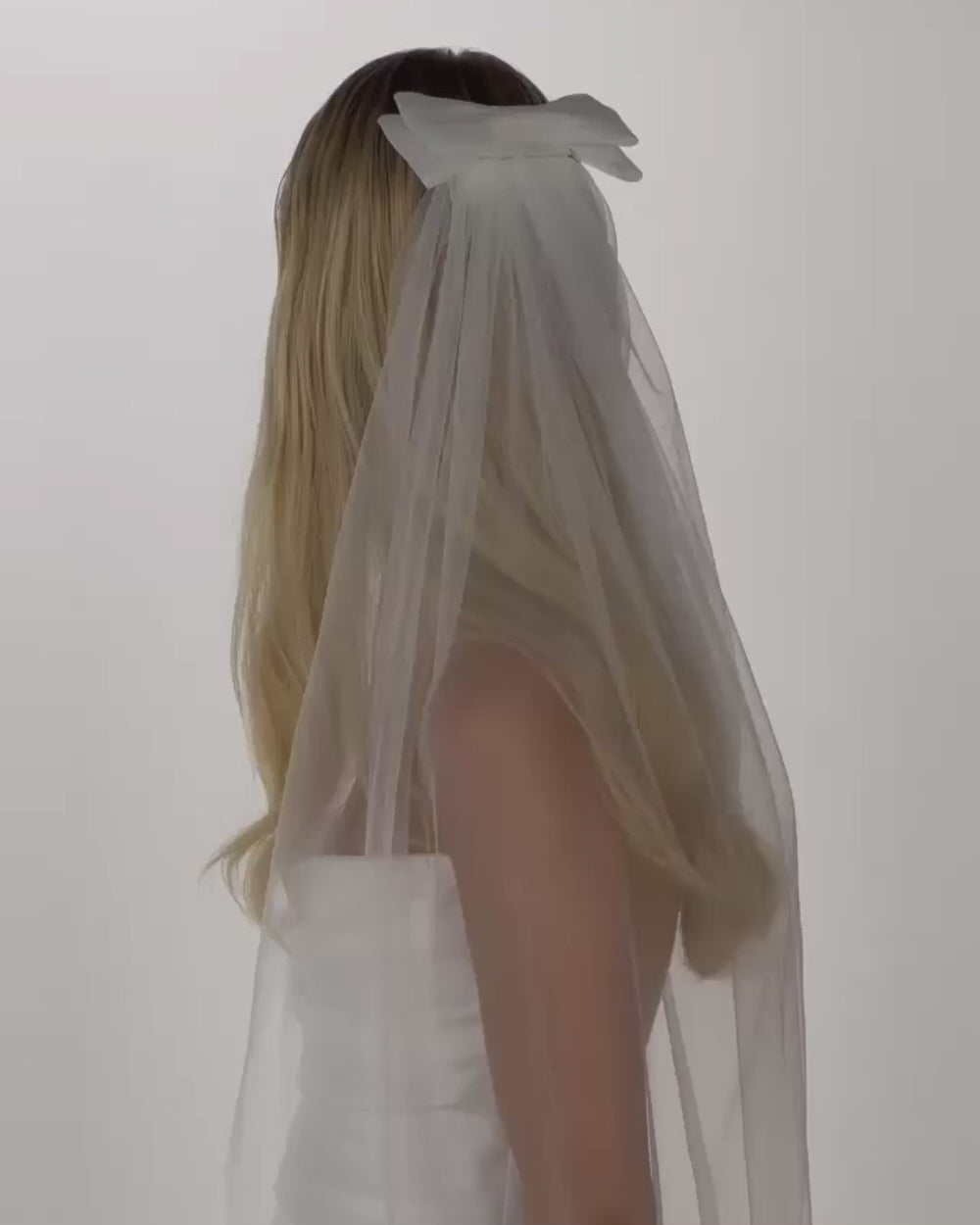 Einer Braut mit offenen Haaren, einer Tüll-Haarschleife und einem Schleier dreht sich hinten nach vorne