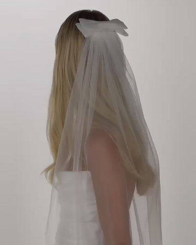 Einer Braut mit offenen Haaren, einer Tüll-Haarschleife und einem Schleier dreht sich hinten nach vorne