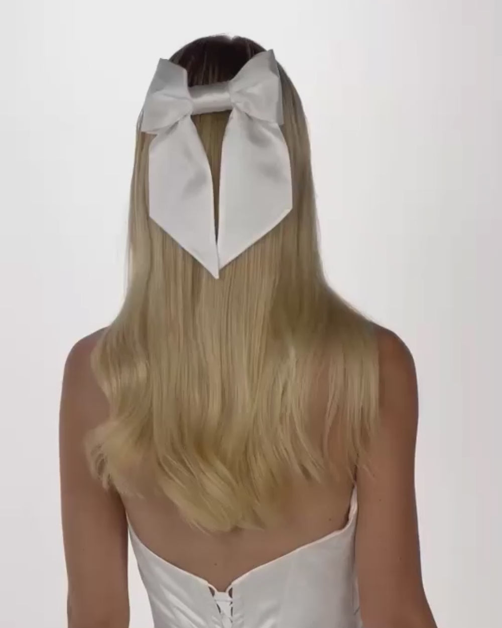 Eine Braut mit offenen Haaren und einer Seidenschleife dreht sich von hinten nach vorne