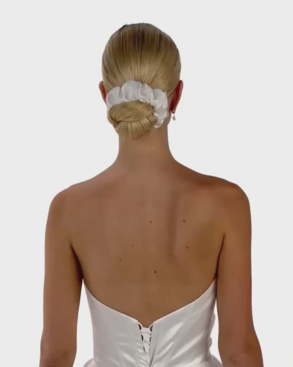Eine Braut mit Bun und gerafften Seiden-Haarband dreht von hinten nach vorne