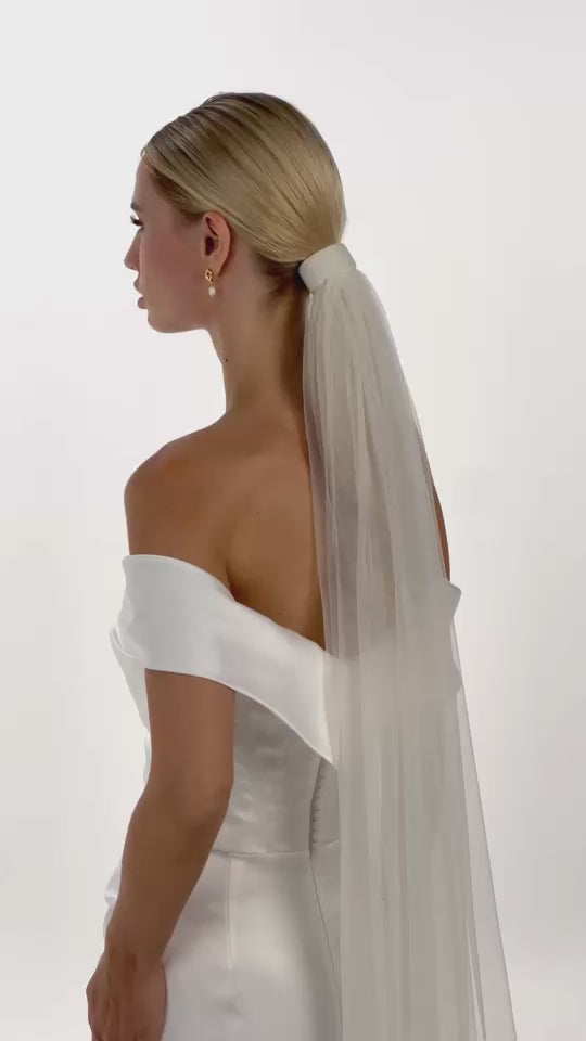 Eine Braut mit einem Tüll-Haarband und Schleier dreht sich von hinten nach vorne