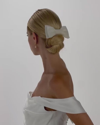 Eine Braut mit cleanen Bun und einer Tüll-Haarschleife dreht sich von hinten nach vorne