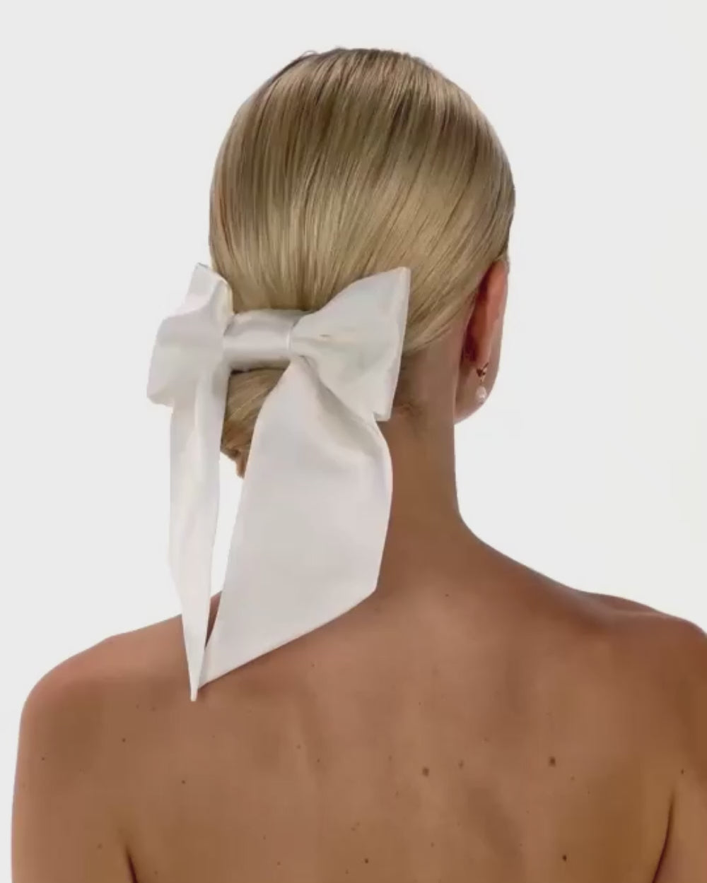 Eine Braut mit cleanen Bun, Seidenhaarband und Seiden-Haarschleife dreht sich von hinten nach vorne