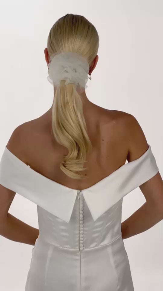 Eine Braut mit einem geraften Tüllharband im Ponytail dreht sich von hinten nach vorne