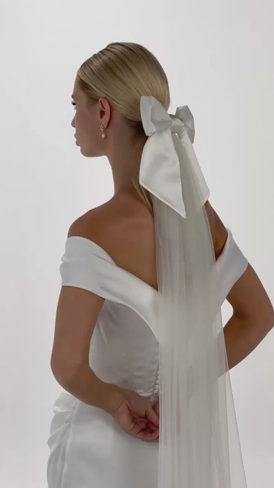 Eine Braut mit Seidenschleife & Schleier im Haar dreht sich von hinten nach vorne