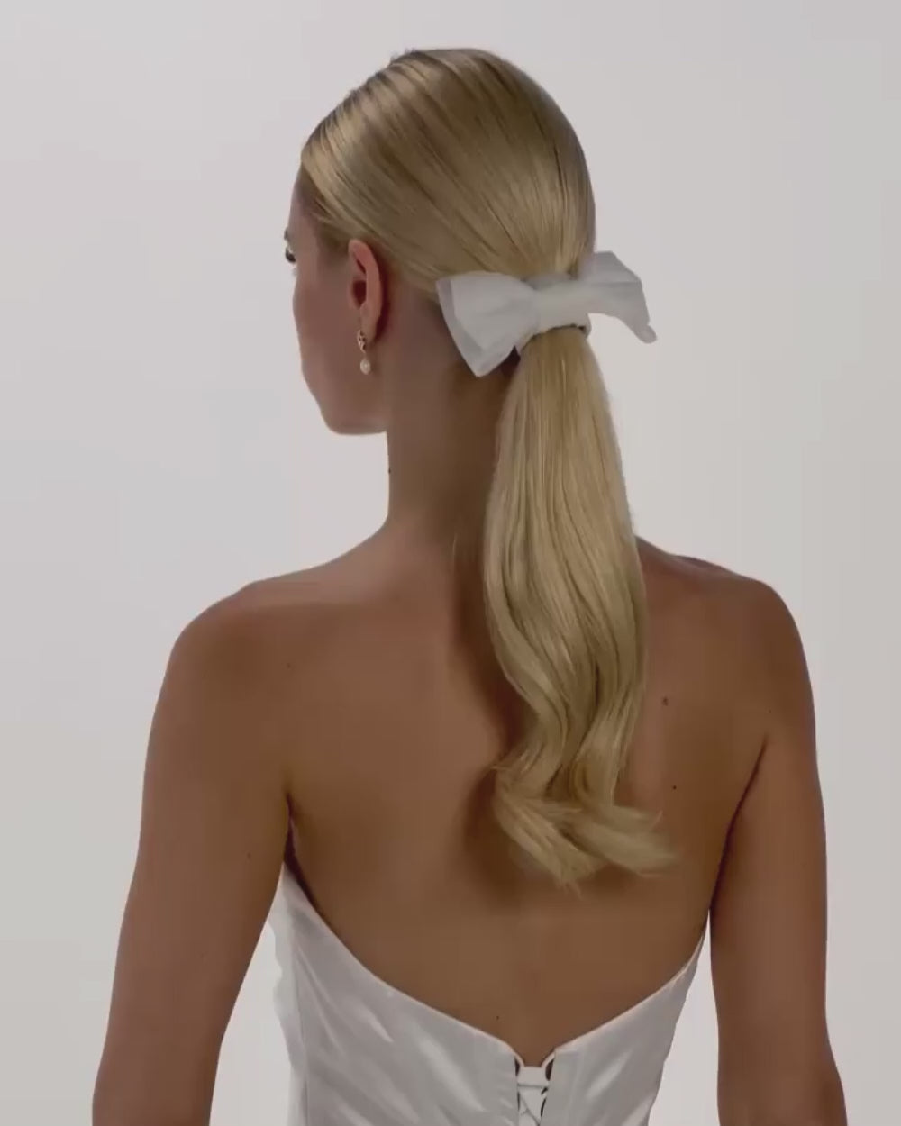Eine Braut mit Ponytail, einem Haarband und einer Tüll-Haarschleife dreht sich von hinten nach vorne