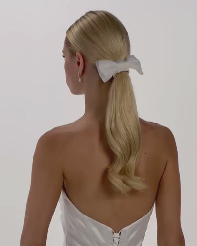 Eine Braut mit Ponytail, einem Haarband und einer Tüll-Haarschleife dreht sich von hinten nach vorne