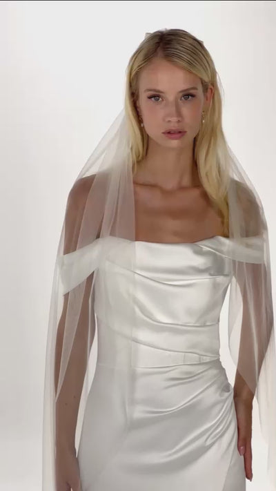 Eine Braut mit Seidenschleife und Schleier in offenen Haaren dreht sich von vorne nach hinten