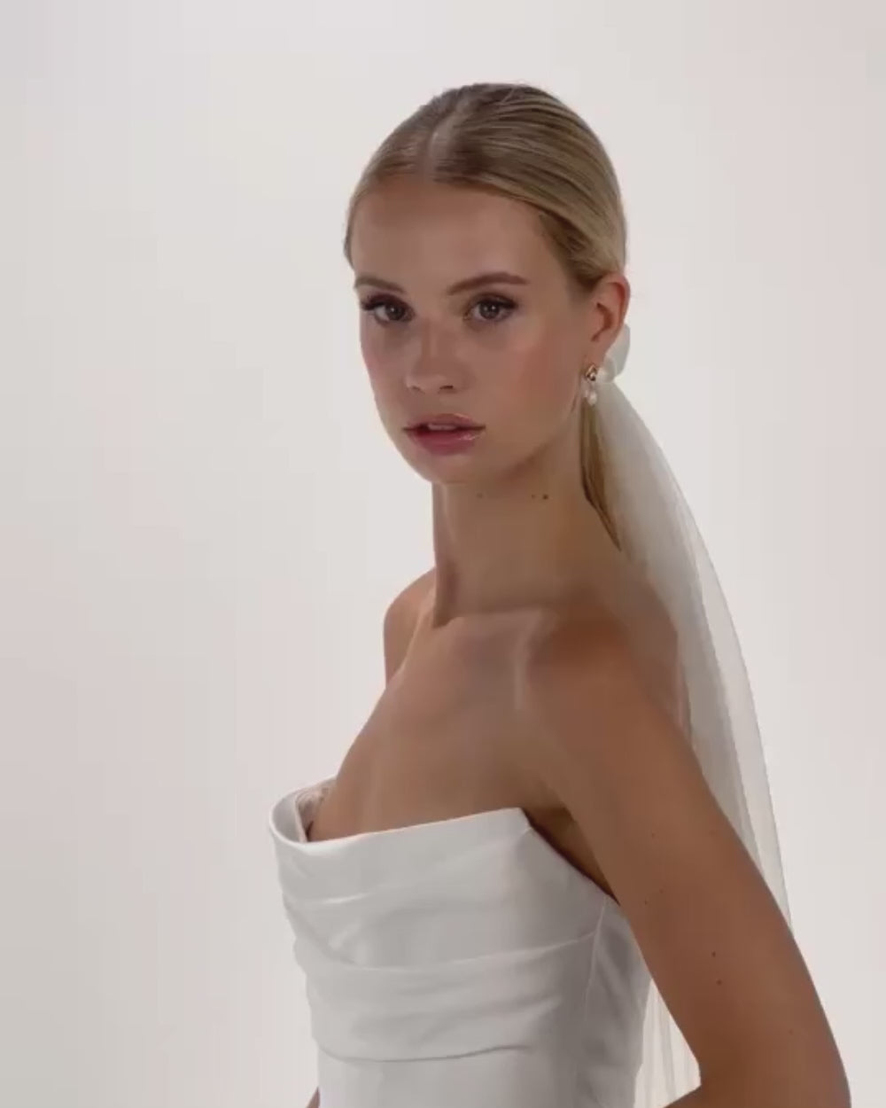 Eine Braut mit Ponytail, gerafften Seidenl-Haarband und Schleier  dreht von vorne nach hinten